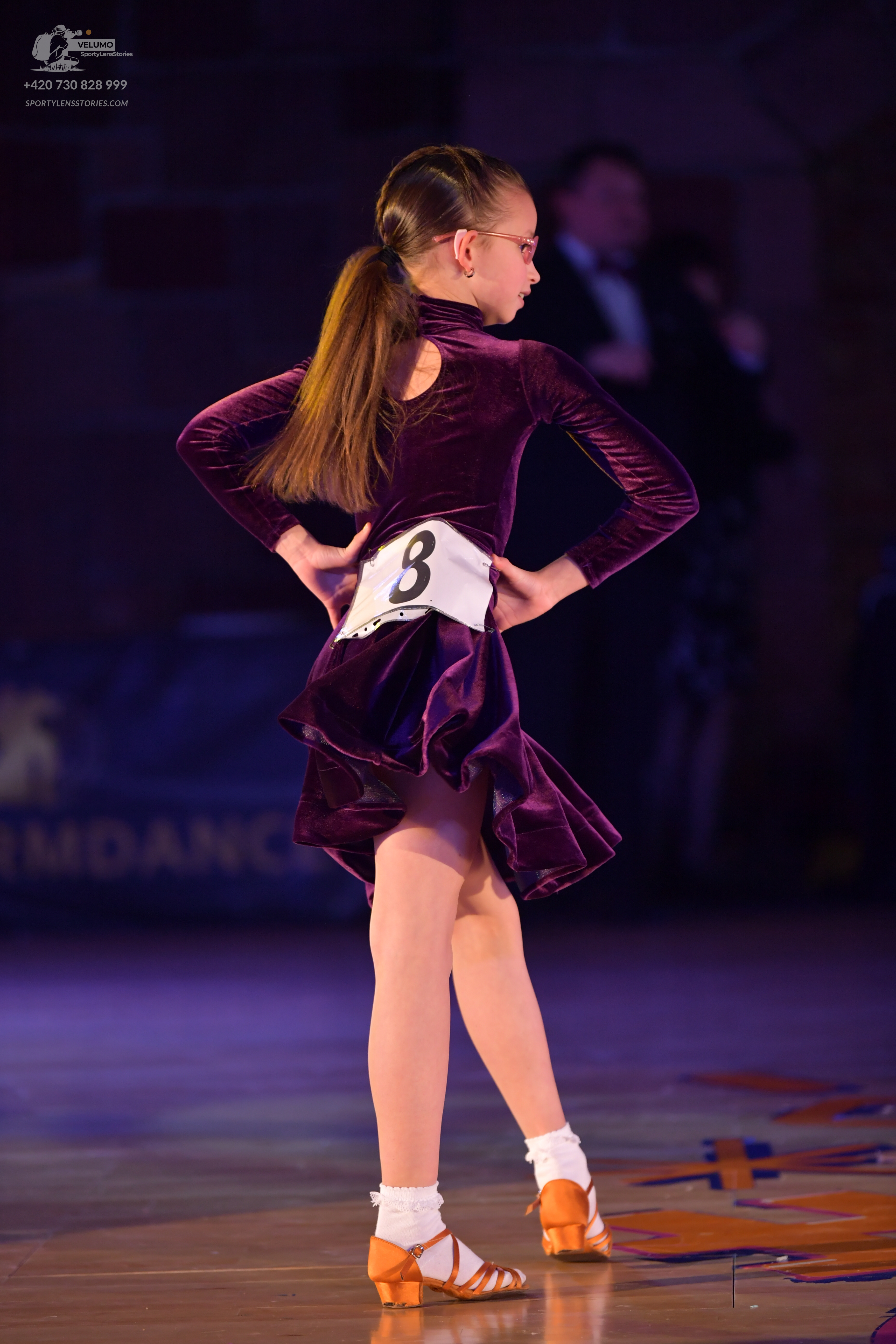 Dancesport competitor: Female dancer: dark purple velvet long-sleeved latin dress with a flared skirt, 