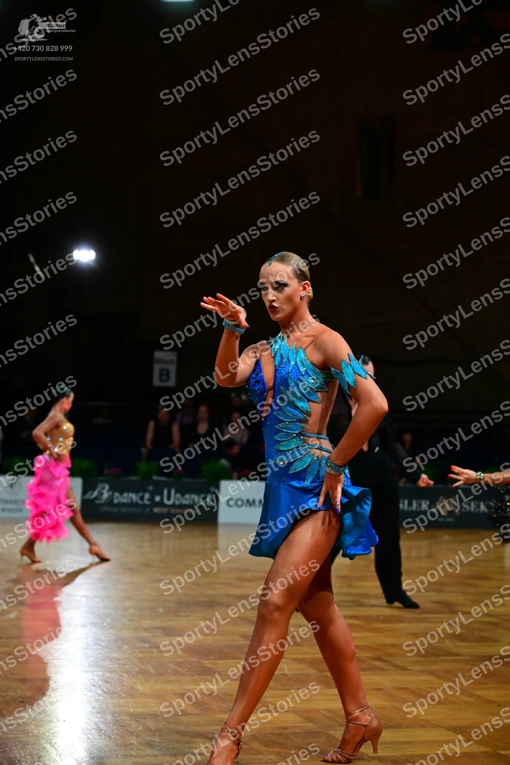 Dancesport competitor: Female dancer (foreground): blue latin dance dress with feather-like sequin patt