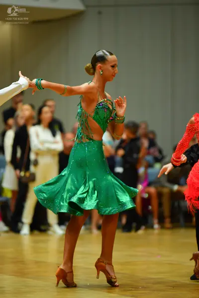 Dancesport competitor: Female dancer: green latin dress with sequins and beaded fringe, green earrings 