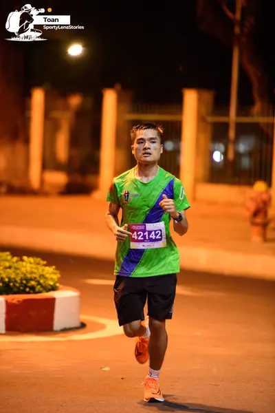 Marathon runner #42142: Runner 1: green and blue jersey, black shorts, orange shoes, and a watch