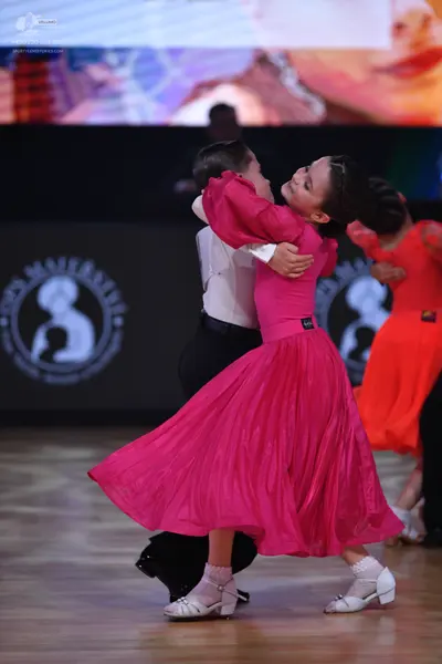 Dancesport competitor: Male dancer in foreground: white long-sleeved shirt and black trousers