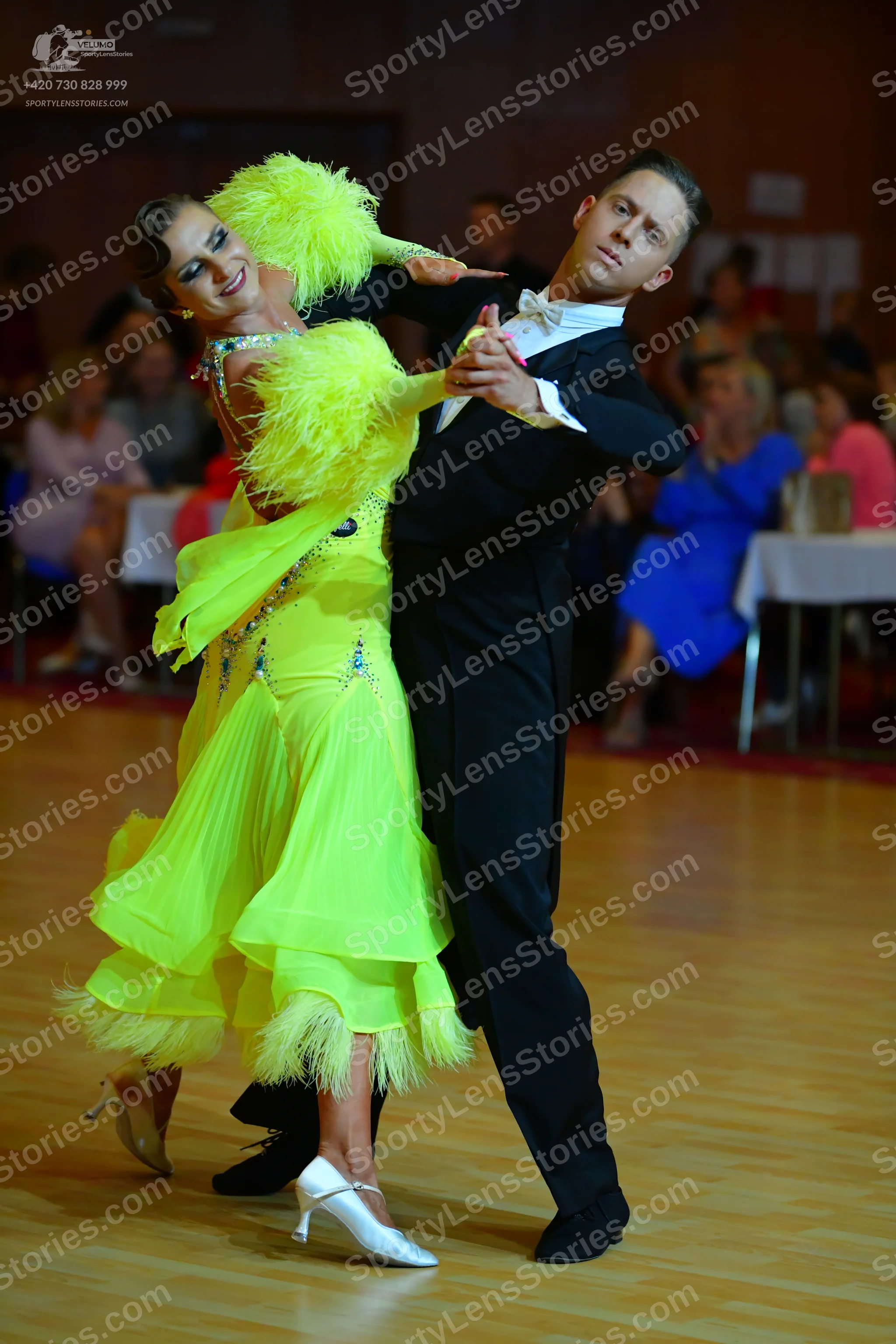 Dancesport competitor: Female dancer: bright yellow dance dress with feather trim on the sleeves and he