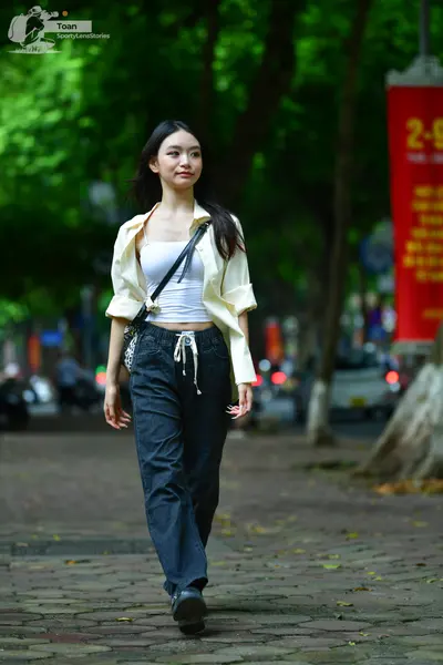 Dancesport competitor: Female subject: white tank top, cream-colored unbuttoned shirt, and dark blue je