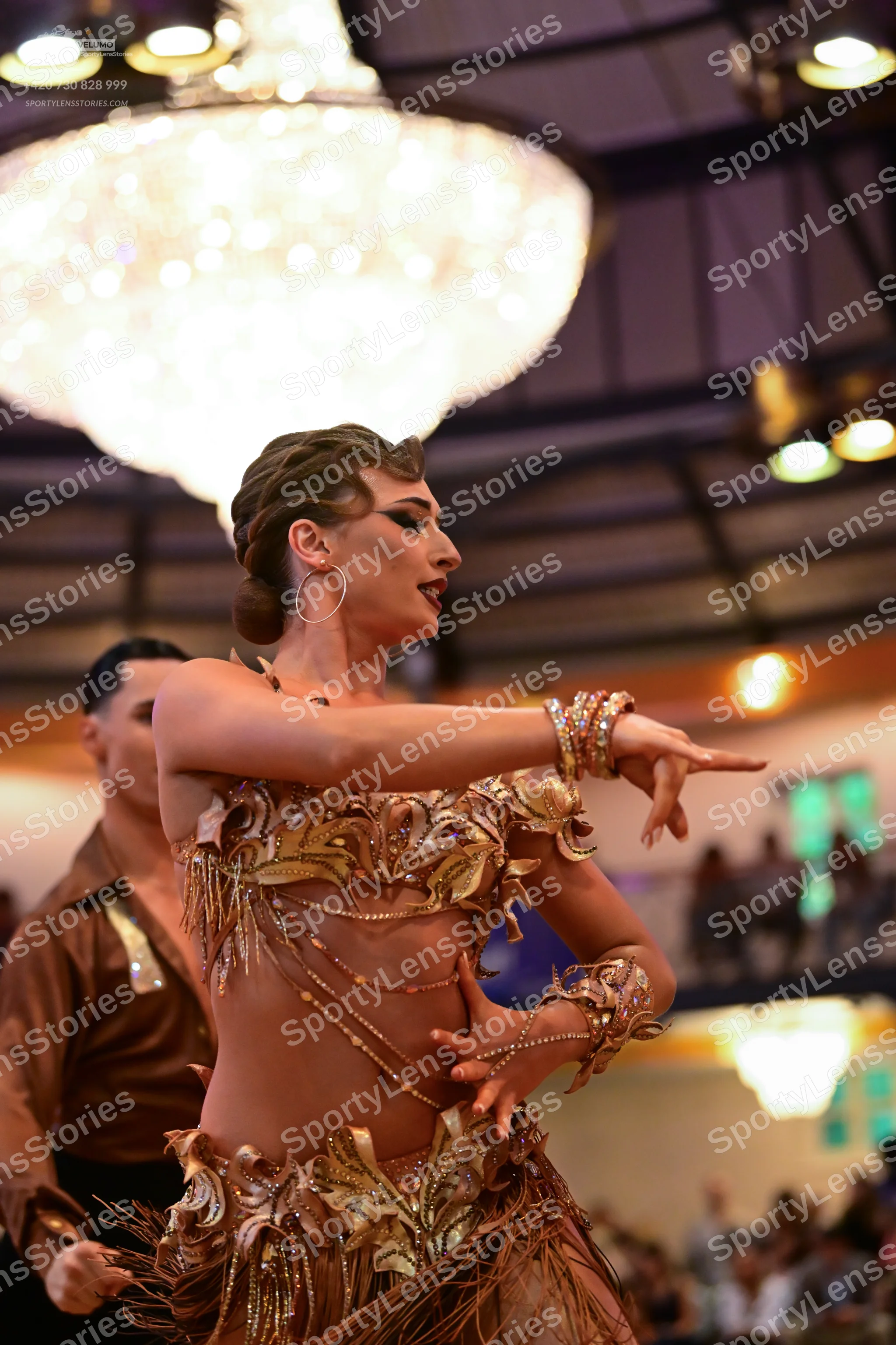 Dancesport competitor: Female dancer: gold/bronze Latin dance costume with intricate sequins, embroider
