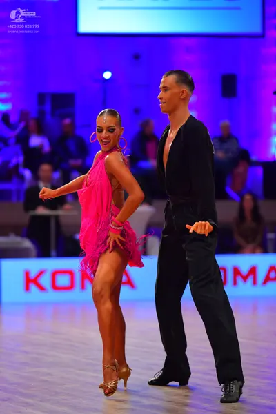 Dancesport competitor: Female dancer: bright pink latin dress with fringe and large hoop earrings