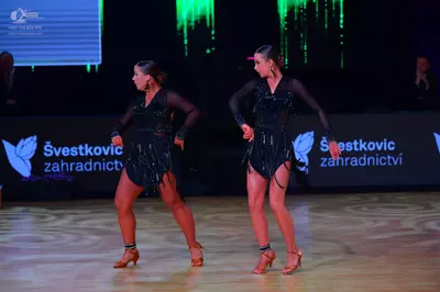 Dancesport competitor: Both dancers: black Latin dance dresses with long sleeves, sequin embellishments