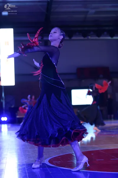 Dancesport competitor: Female dancer: black ballroom gown with red sequin patterns and a red layered he