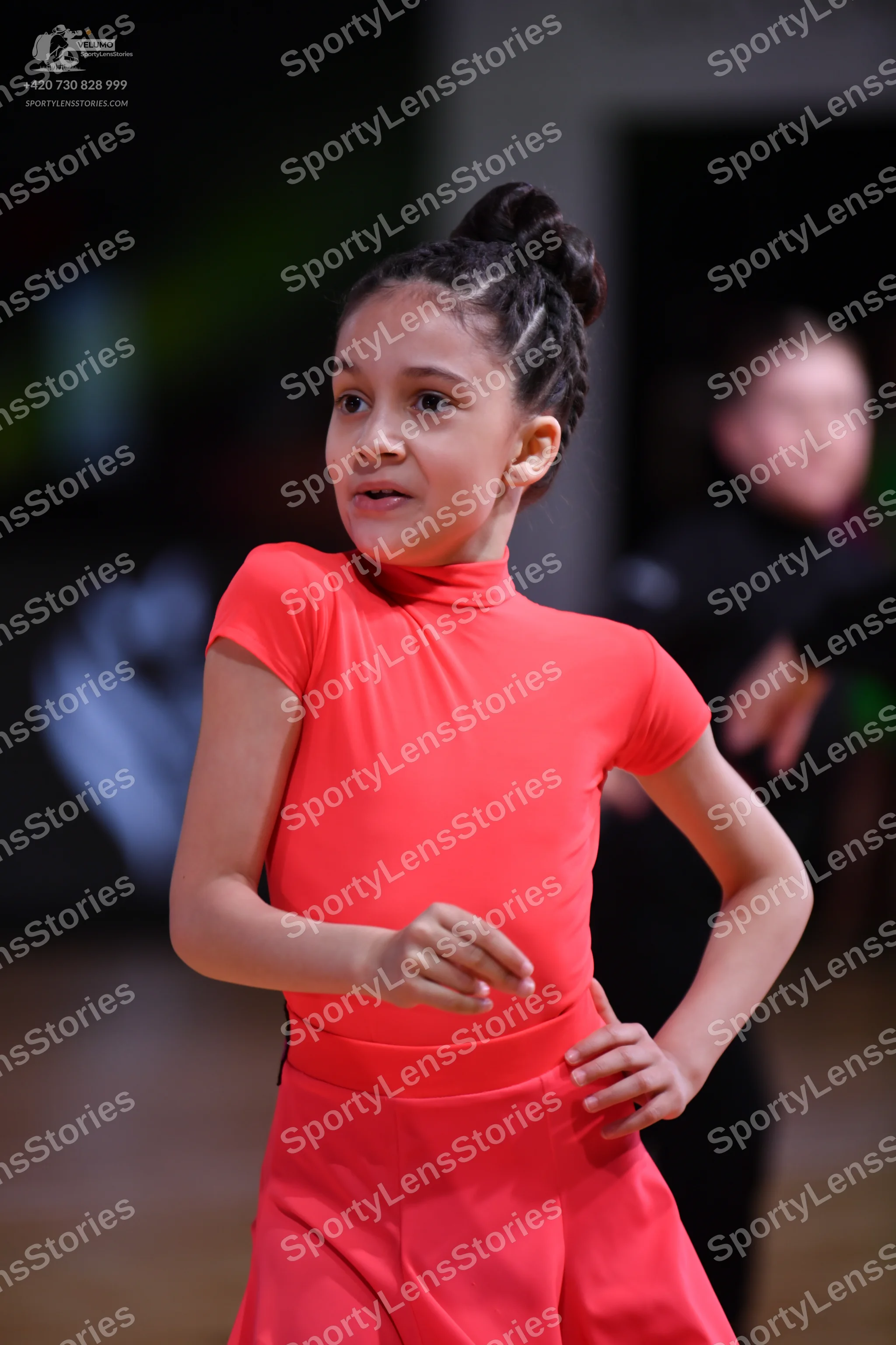Dancesport competitor: Female dancer: bright coral-colored short-sleeved top and matching skirt in a sm