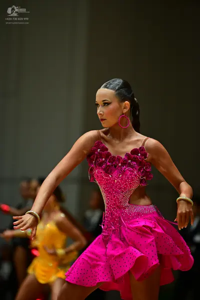 Dancesport competitor: Female dancer in foreground: bright pink latin dress with black rhinestones, 3D 