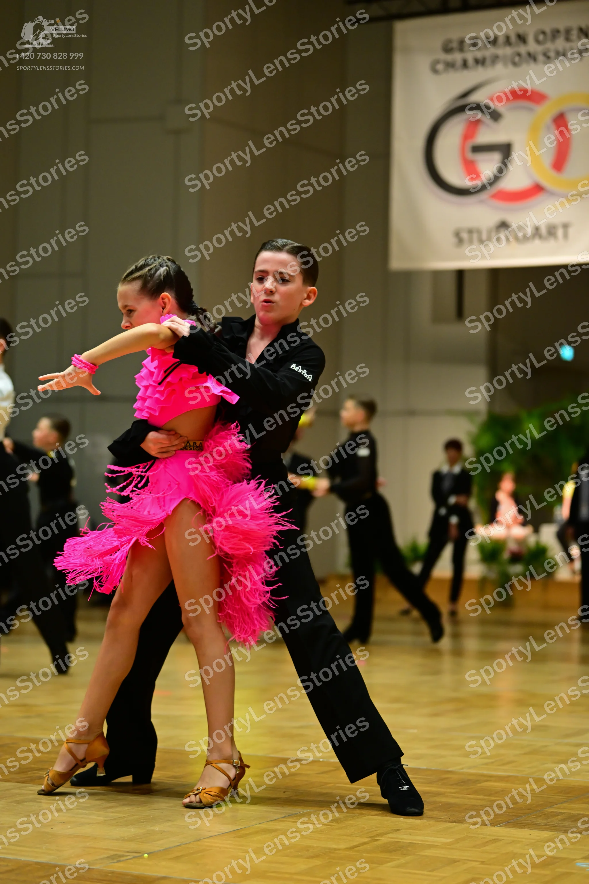 Dancesport competitor: Female dancer: bright pink Latin dress with a voluminous, fringed skirt