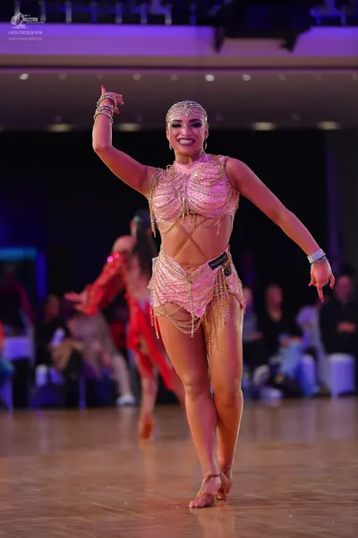 Dancesport competitor: Female dancer: nude-colored two-piece Latin costume with gold chain fringe and s