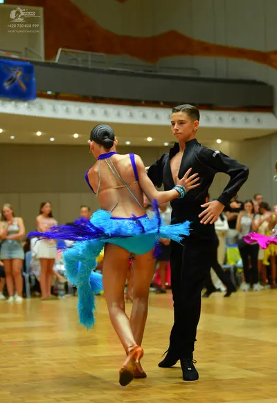 Dancesport competitor: Female dancer: bright blue Latin dance dress with long, flowing fringe and thin 