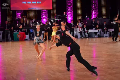 Dancesport competitor: Female dancer in foreground: black Latin dance dress with silver sequin and bead