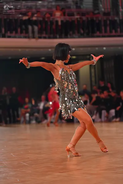 Dancesport competitor: Female dancer: silver latin dress covered in large sequins, with silver bracelet