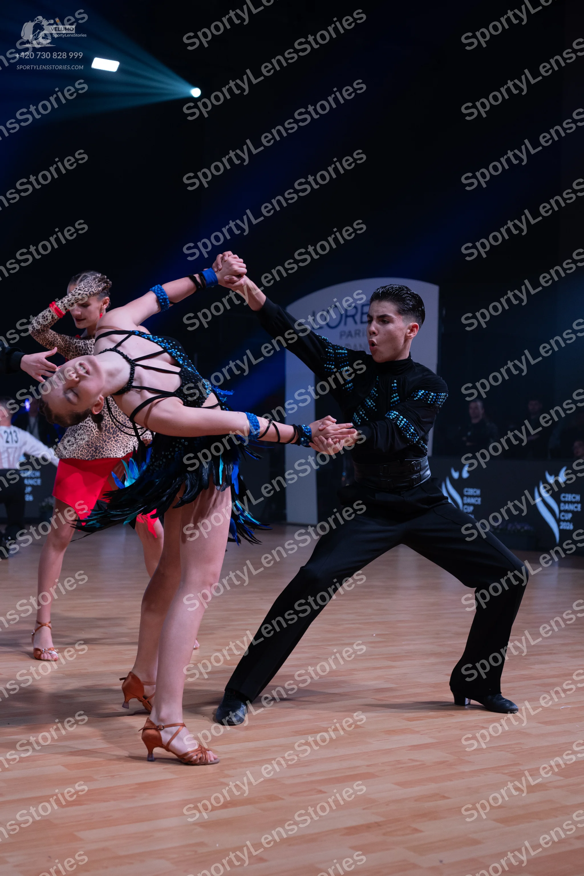 Dancesport competitor: Male dancer: black long-sleeved shirt with blue/teal patterns and black trousers