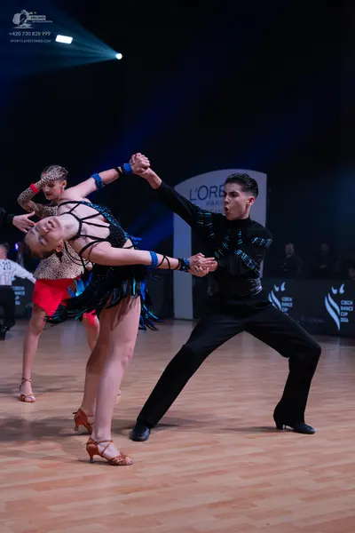Dancesport competitor: Male dancer: black long-sleeved shirt with blue/teal patterns and black trousers