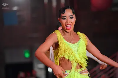 Dancesport competitor: Female dancer: neon yellow Latin dance dress with fringe, rhinestones, and cutou