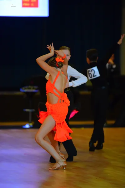 Dancesport competitor #62: Female dancer: vibrant orange latin dress with an orange hair accessory