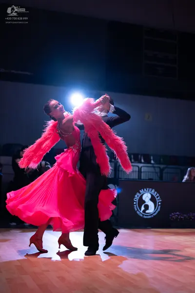 Dancesport competitor: Female dancer: bright pink ballroom dress with a full, flowing skirt and large, 