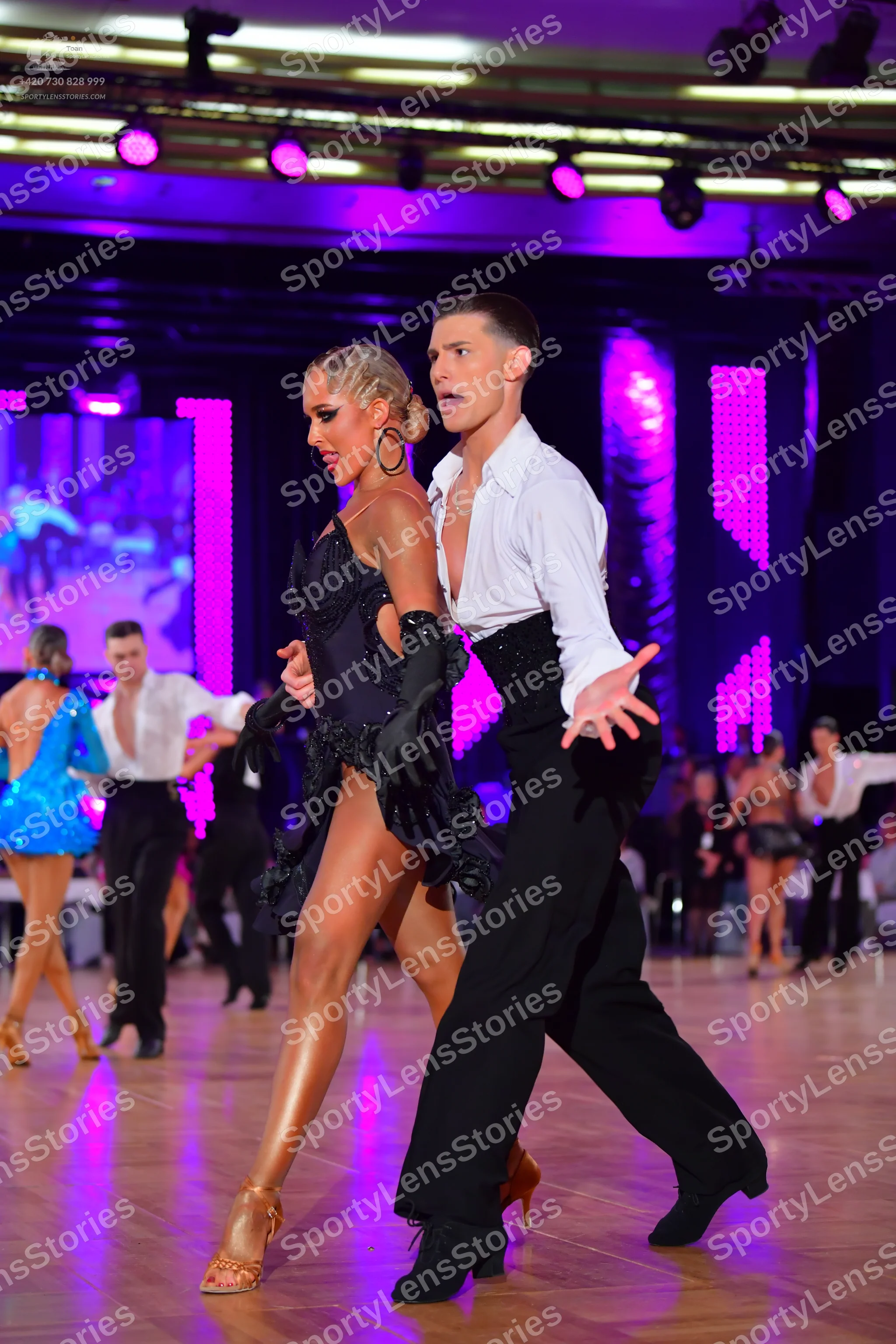Dancesport competitor: Main female dancer: black sequined latin dress with long black gloves and large