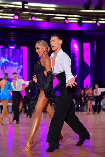 Dancesport competitor: Main female dancer: black sequined latin dress with long black gloves and large 