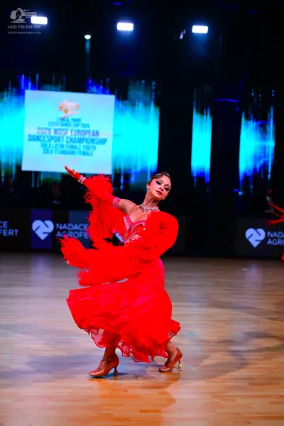 Dancesport competitor: Female dancer: red latin dress with voluminous flowing sleeves and a layered ski