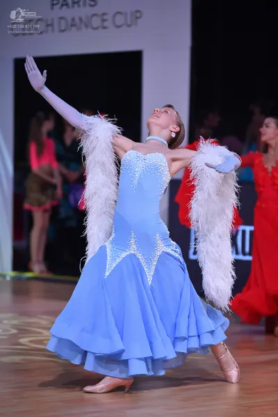 Dancesport competitor: Female dancer in foreground: light blue ballroom gown with silver-toned embellis
