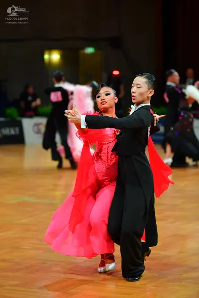 Dancesport competitor: Female dancer: bright pink Latin dance dress with a textured bodice and a flowin