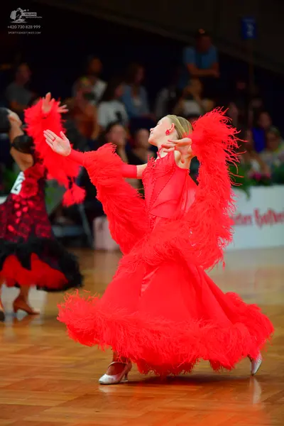Dancesport competitor: Female dancer in foreground: red ballroom dress with voluminous red feather frin