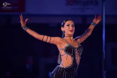 Dancesport competitor: Female dancer: black latin dress heavily embellished with rhinestones, featuring