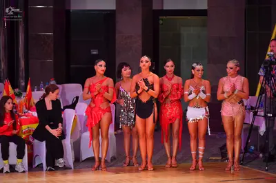 Dancesport competitor: Female dancer 1: red/orange latin dress with thin straps and a ruffled skirt