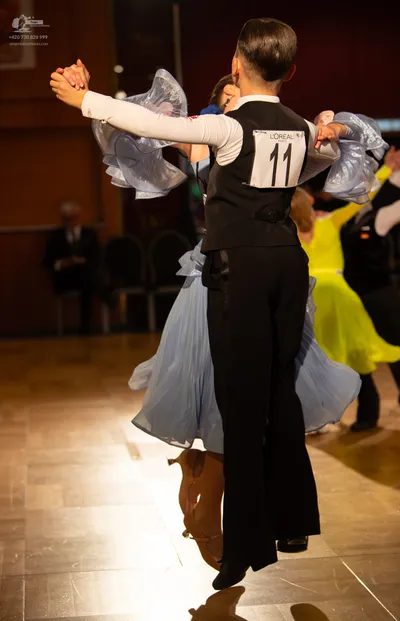 Dancesport competitor #11: Male dancer: black waistcoat, white long-sleeved shirt with large light blue ruf