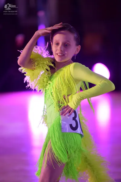Dancesport competitor: Female dancer: lime green latin dress with long sleeves and fringe