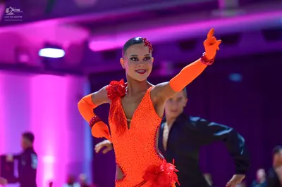 Dancesport competitor: Female dancer: bright orange latin dance dress covered in sequins with large red