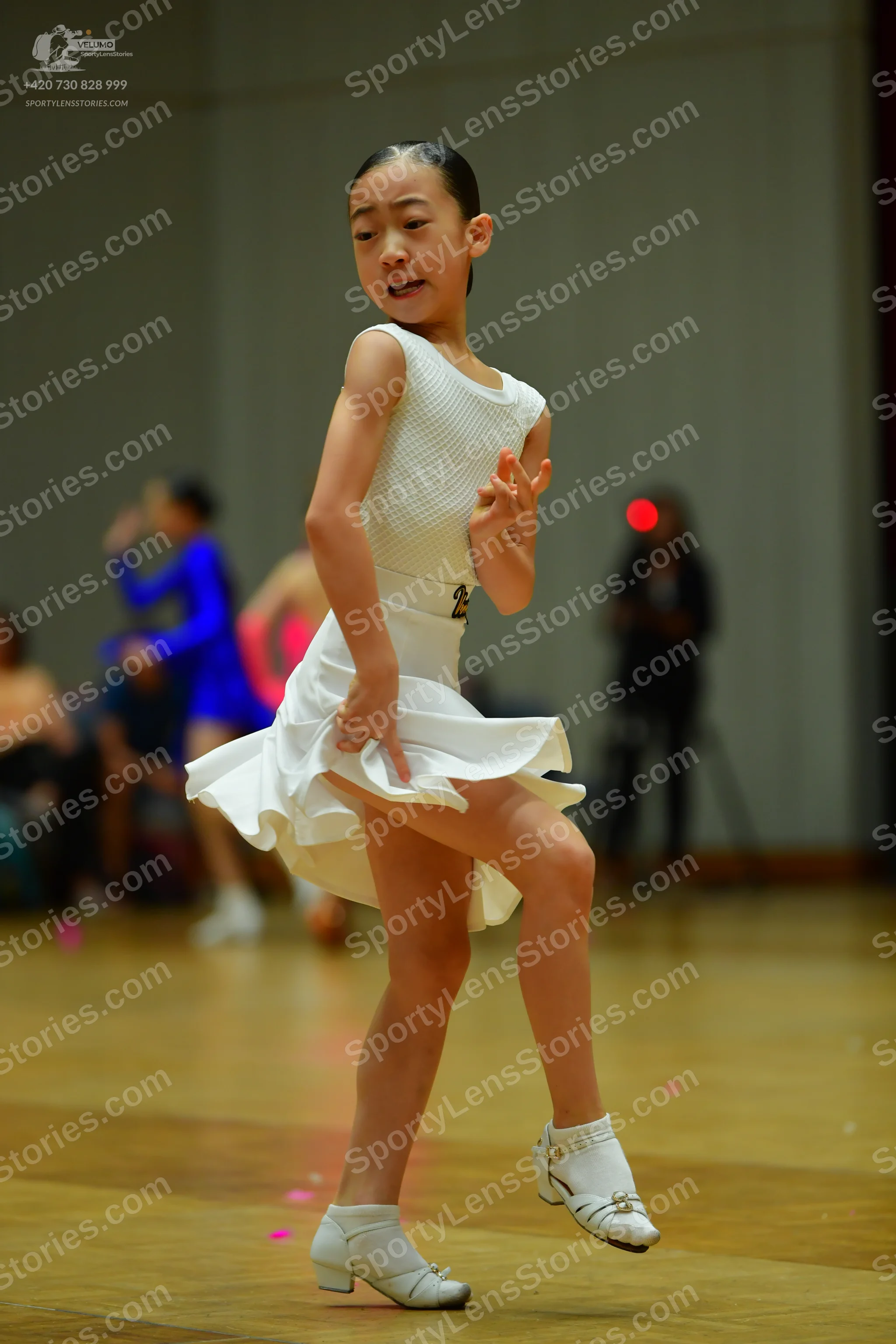 Dancesport competitor: Female dancer: white sleeveless dress with a flared skirt and a small belt