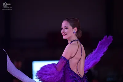 Dancesport competitor: Female dancer: purple/lavender sequined dance dress with large purple and white 