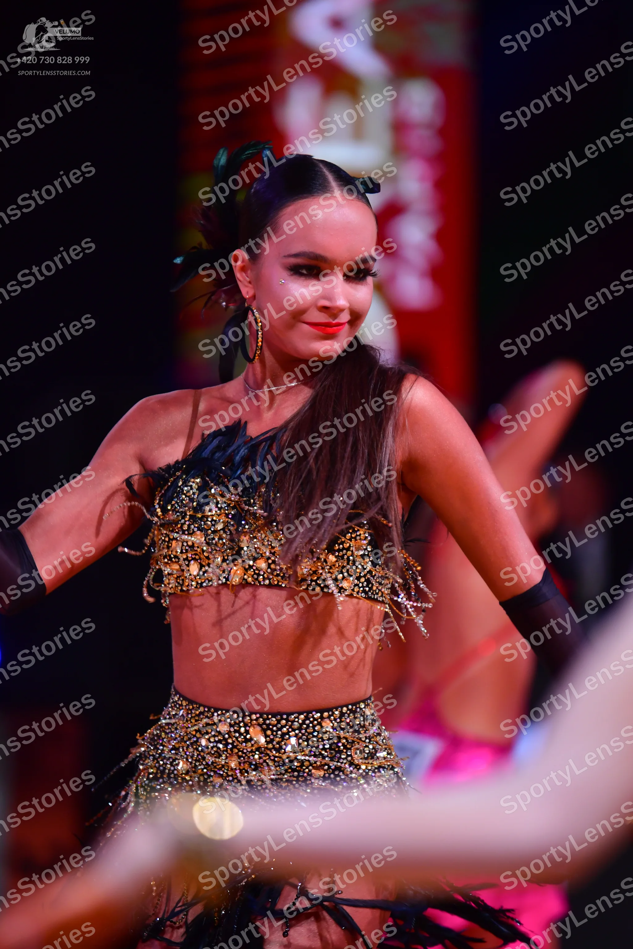Dancesport competitor: Female dancer: black and gold two-piece latin dance costume with heavy gold/bron