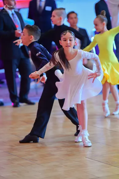 Dancesport competitor: Male dancer: black long-sleeved shirt with "SKF" lettering on the sleeve and bla