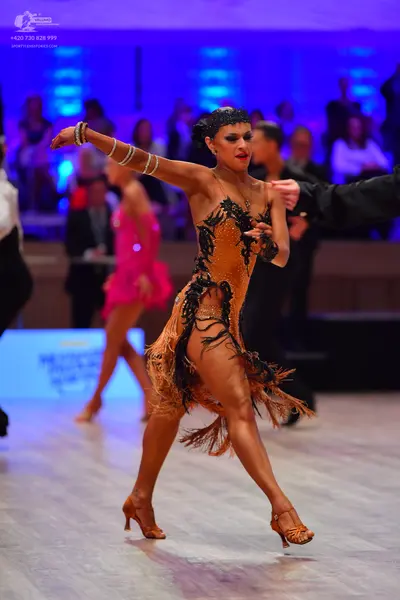 Dancesport competitor: Main female dancer: nude-colored Latin dance dress with black sequin/lace patter