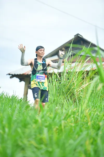 Marathon runner #3058: Runner 1: dark blue/black tank top with green/yellow pattern, dark blue/black sh