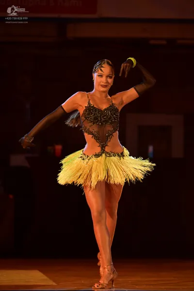 Dancesport competitor: Female dancer: black latin dance costume with a sheer, beaded bodice and a short