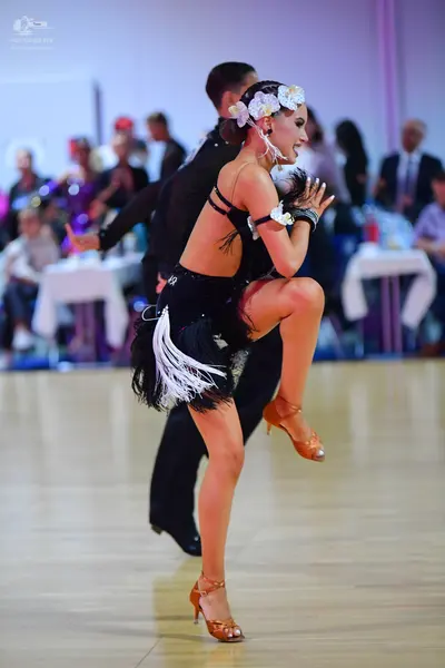 Dancesport competitor: Female dancer: black Latin dance dress with white fringe on the skirt and white 