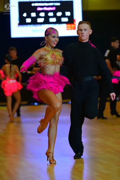 Dancesport competitor: Female dancer: bright pink and gold Latin dance dress with a gold sequin bodice,