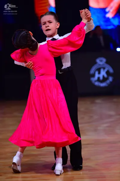 Dancesport competitor: Female dancer: bright pink long-sleeved dress with a full, flowing skirt