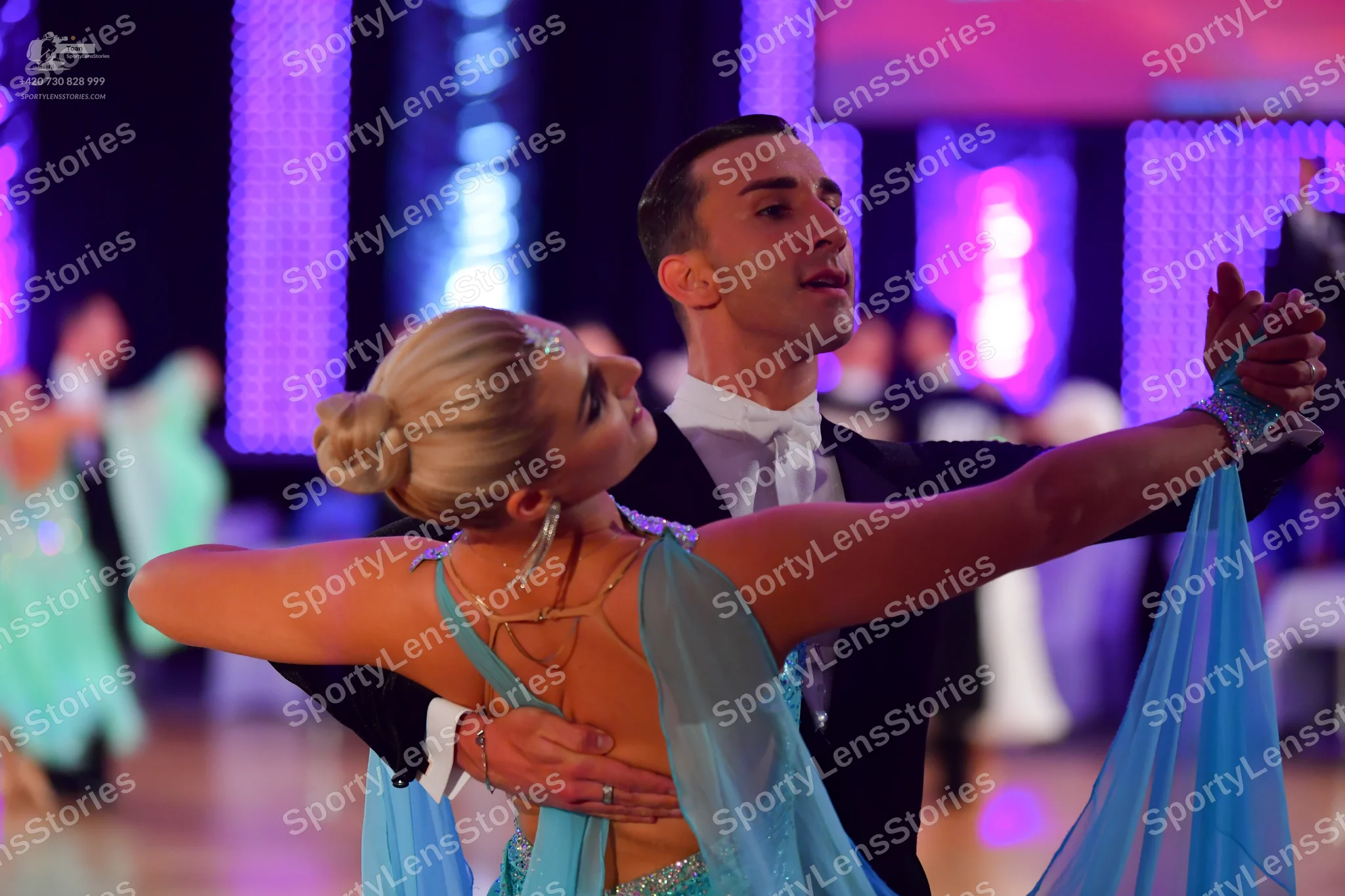 Dancesport competitor: Female dancer: light blue latin dress with sheer, flowing sleeves and thin strap