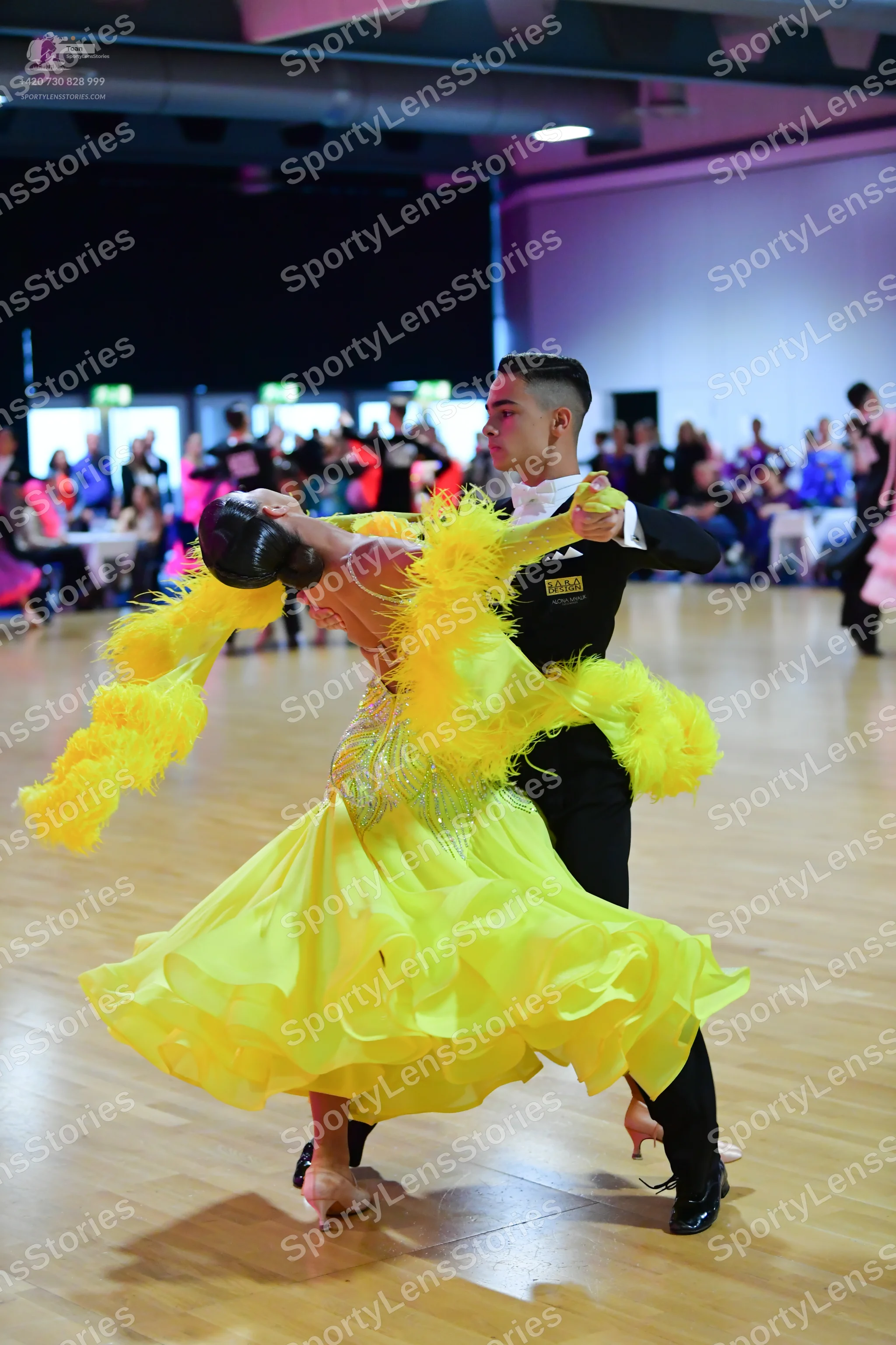 Dancesport competitor: Female dancer: vibrant yellow ballroom dress with a full, tiered, ruffled skirt