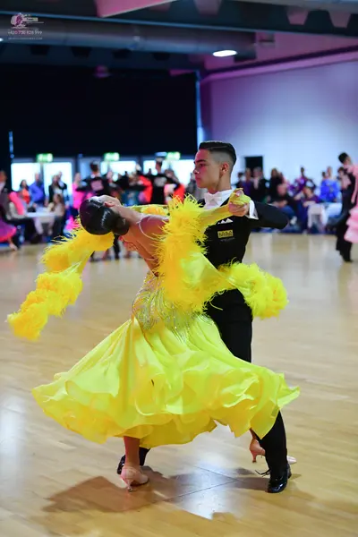 Dancesport competitor: Female dancer: vibrant yellow ballroom dress with a full, tiered, ruffled skirt 