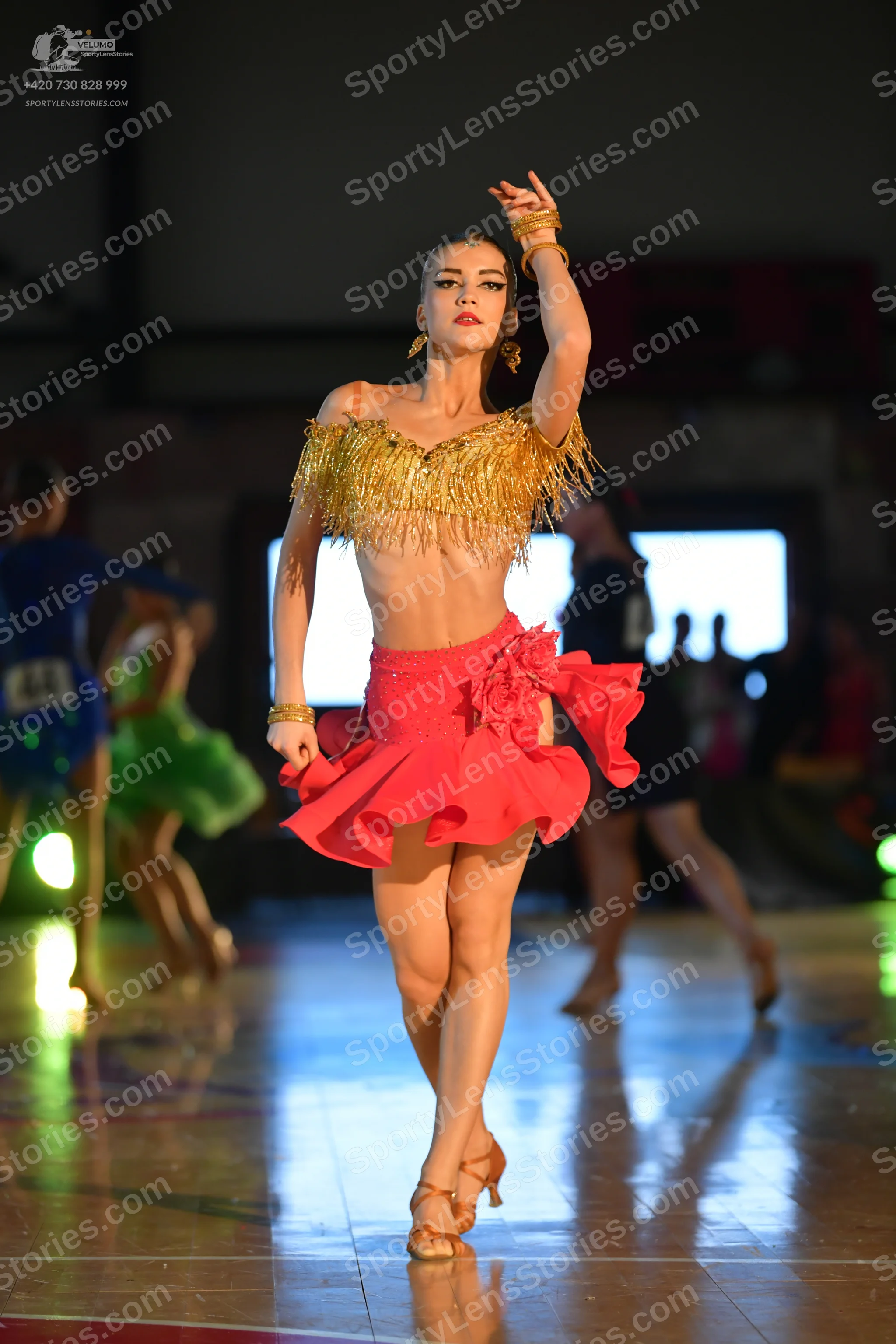 Dancesport competitor #46: Main dancer: coral latin dress with a ruffled skirt, a gold fringe crop top, and