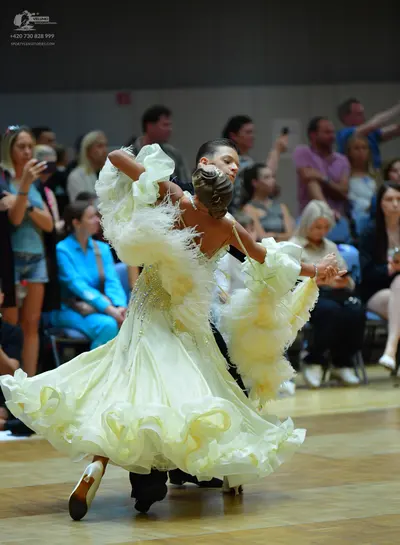 Dancesport competitor: Female dancer: light yellow, voluminous ballgown with many layers of ruffles and