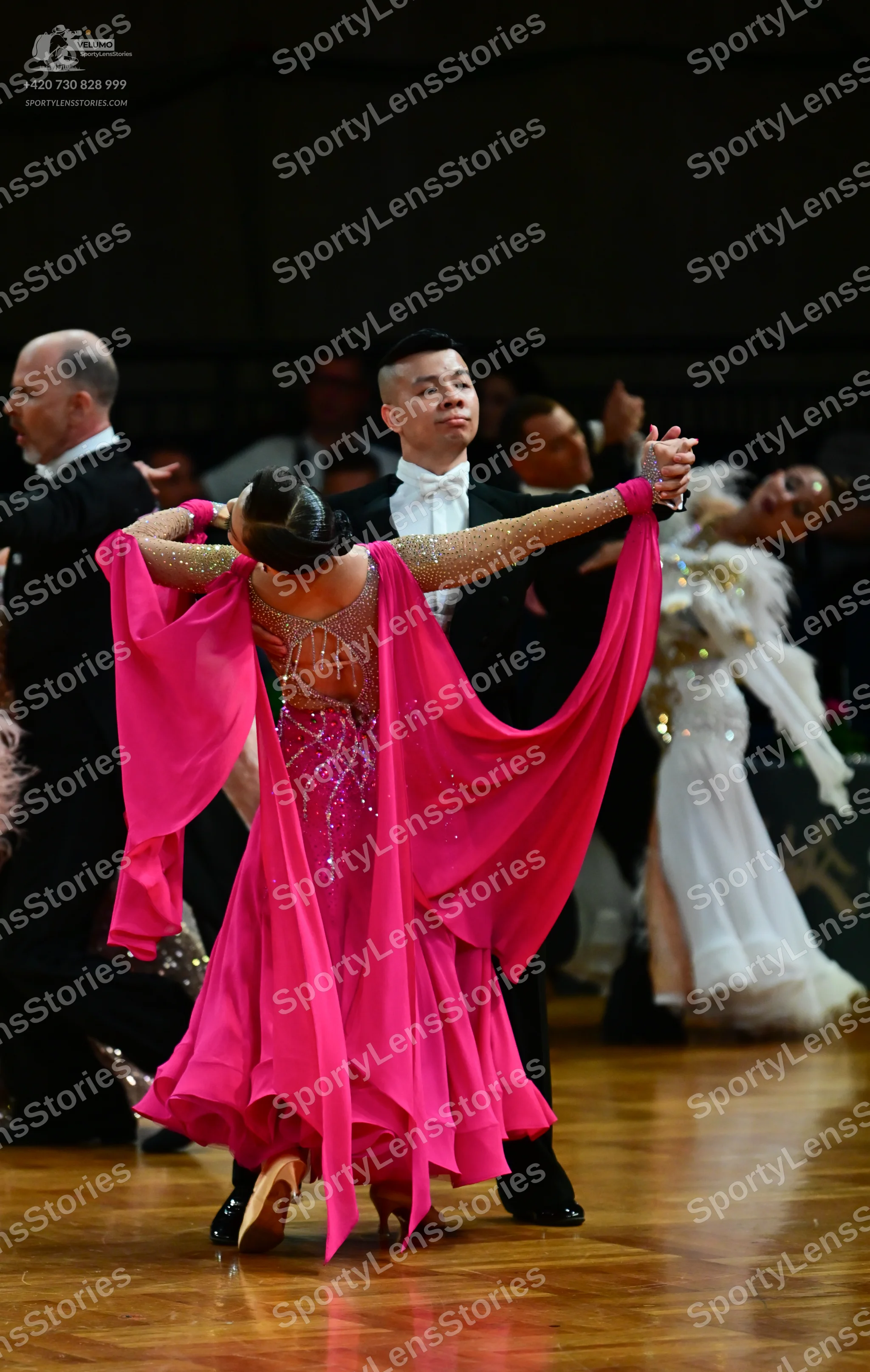 Dancesport competitor: Female dancer: pink ballgown with a sequined bodice and long, sheer, flowing sle